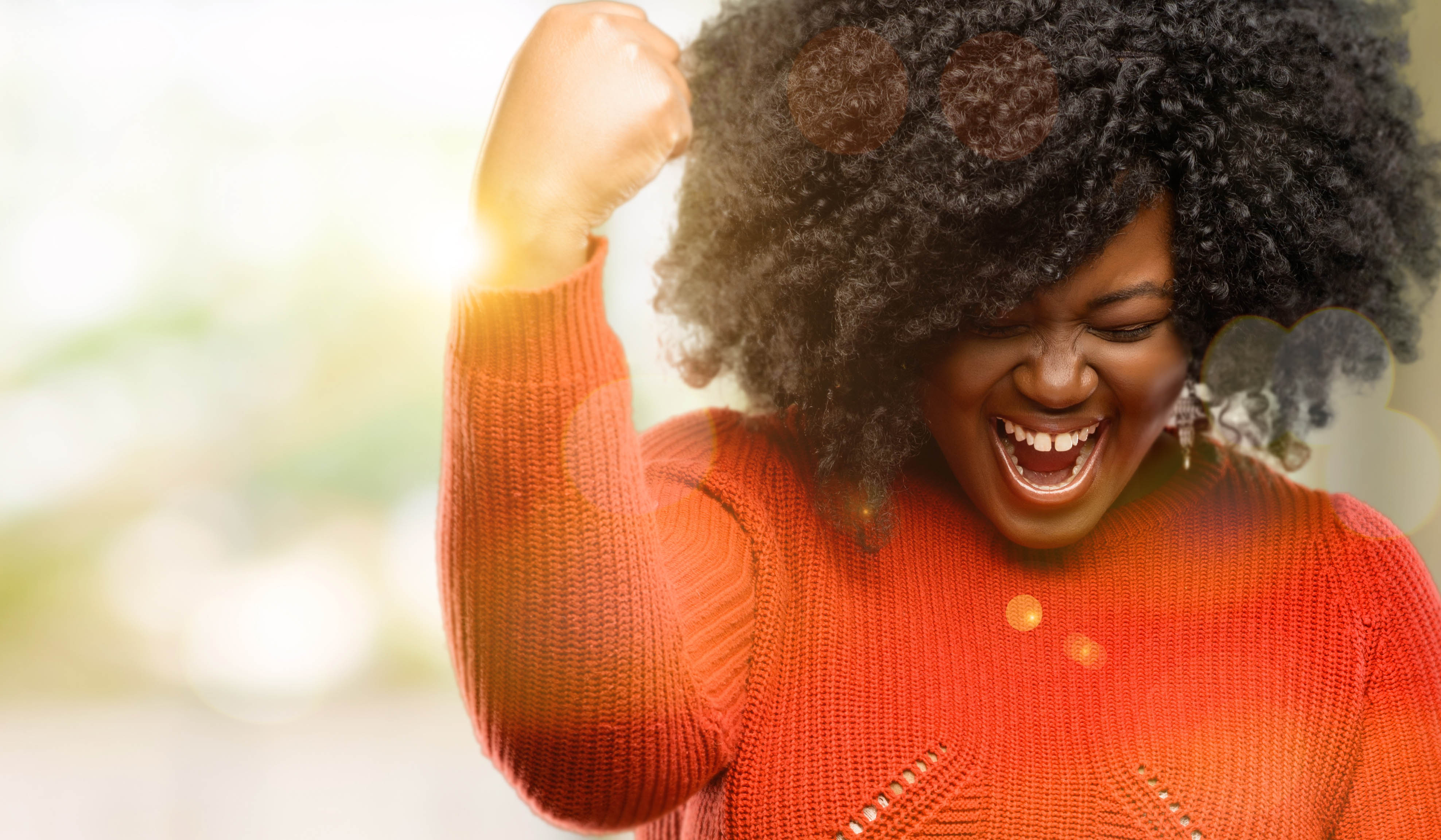 Happy, young black woman celebrating with a hand in the air